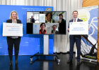 Gruppenbild der Gewinner der Aktion STADTRADELN 2021 (am Bildschirm) mit Bayerns Verkehrsministerin Kerstin Schreyer und AGFK-Vorsitzendem Matthias Dießl, die jeweils mit einem Gratulationsschild links und rechts vom Bildschirm stehen 