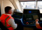 Auf diesem Foto ist Staatsminister Christian Bernreiter mit einer orangenen Warnfeste in dem Cockpit eines Güterzugs zu sehen. 