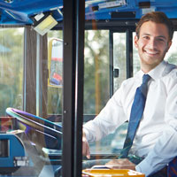 Ein Busfahrer lächelt durch die Scheibe eines Buses