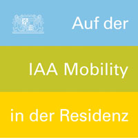 Blauer, grüner und gelber Balken übereinander. In der linken Ecke das kleine Staatswappen. Rechts auf die Balken verteilt der Text "Auf der IAA Mobility in der Residenz"