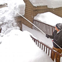 Ein Mann räumt ein Dach von Schnee frei