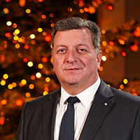 Porträt von Staatsminister Christian Bernreiter. Im Hintergrund ist ein beleuchteter Weihnachtsbaum zu sehen.